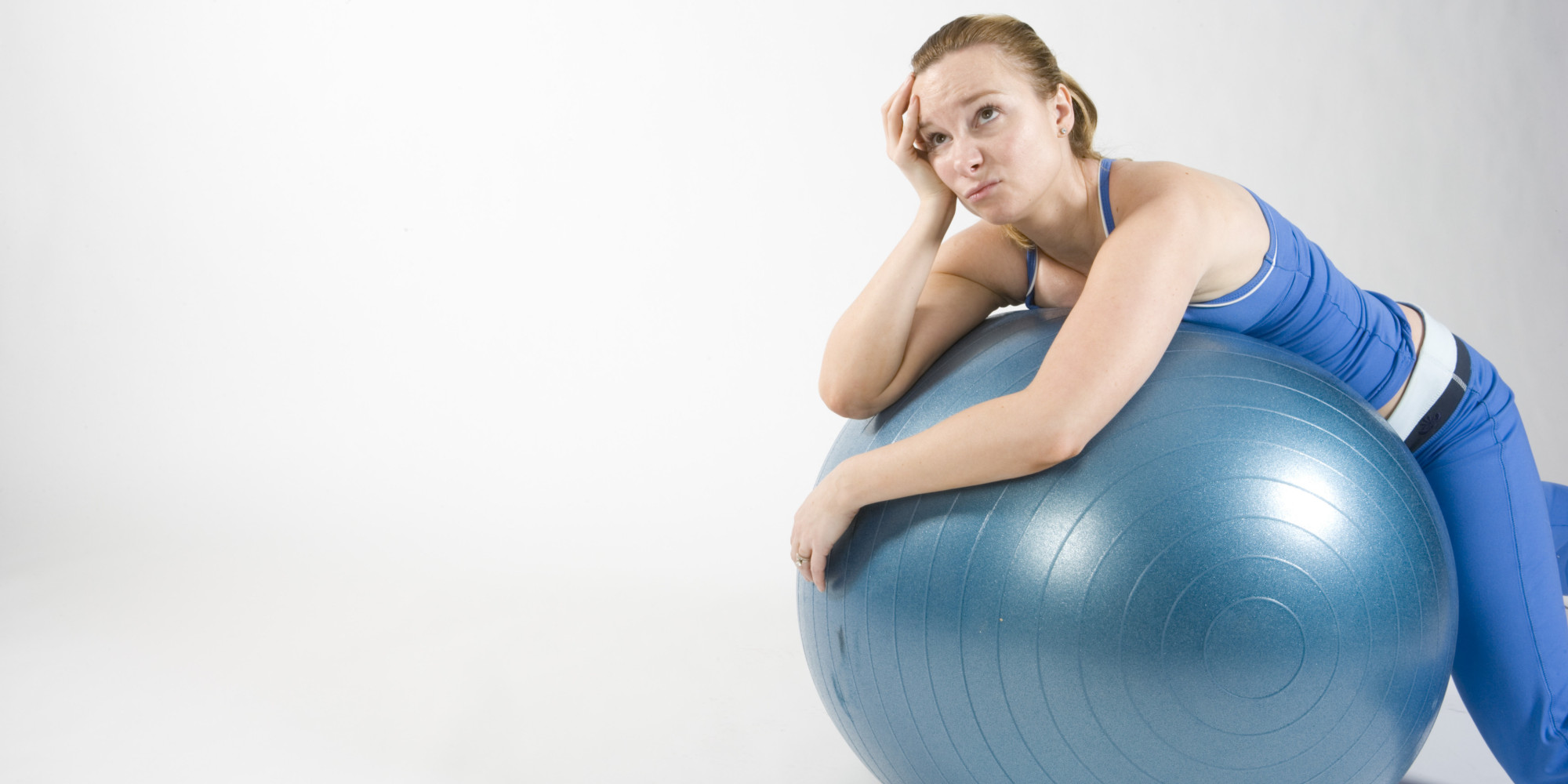 Een foto van een vrouw die gefrustreerd op een fitness bal ligt.