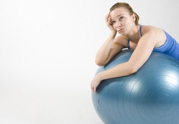 Een foto van een vrouw die gefrustreerd op een fitness bal ligt.